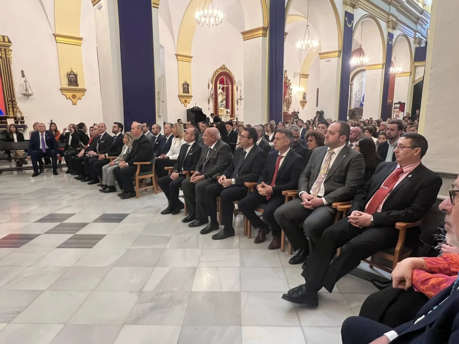 Representantes de las hermandades y autoridades sentados en la nave de la iglesia durante un acto de la Agrupación