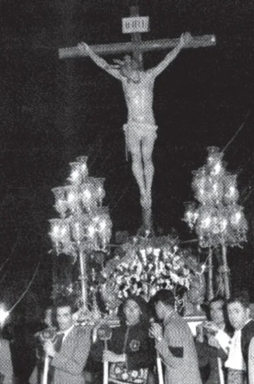 The Santo Cristo de la Vera+Cruz on its trono at night, among its bearers, in a historic photograph.
