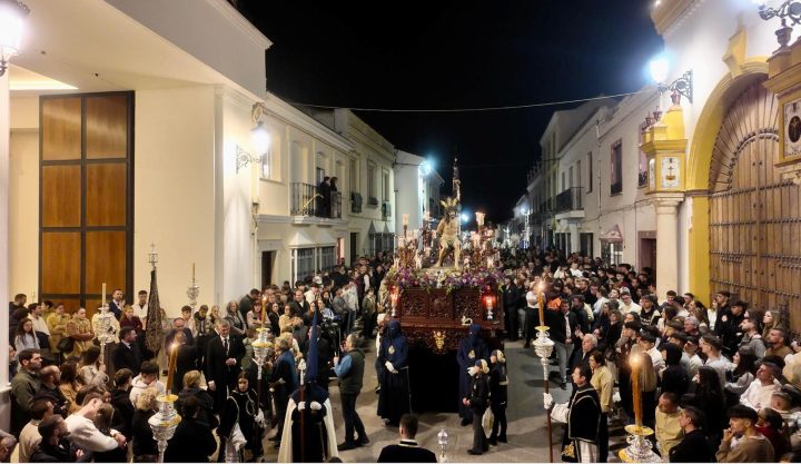 The trono of the Cristo Ultrajado through Campillos at night, among nazarenos and onlookers
