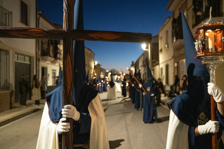 Nazarenos of the Cristo Ultrajado in blue capirotes, carrying the leading cross and a lantern