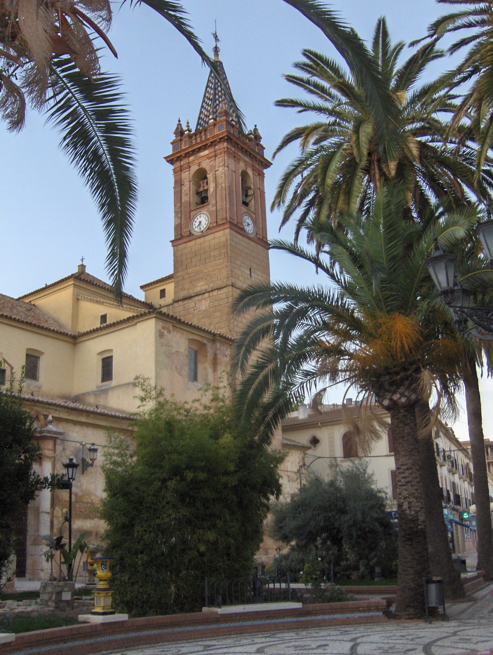 Torre de la Iglesia de Santa María del Reposo entre palmeras, al atardecer