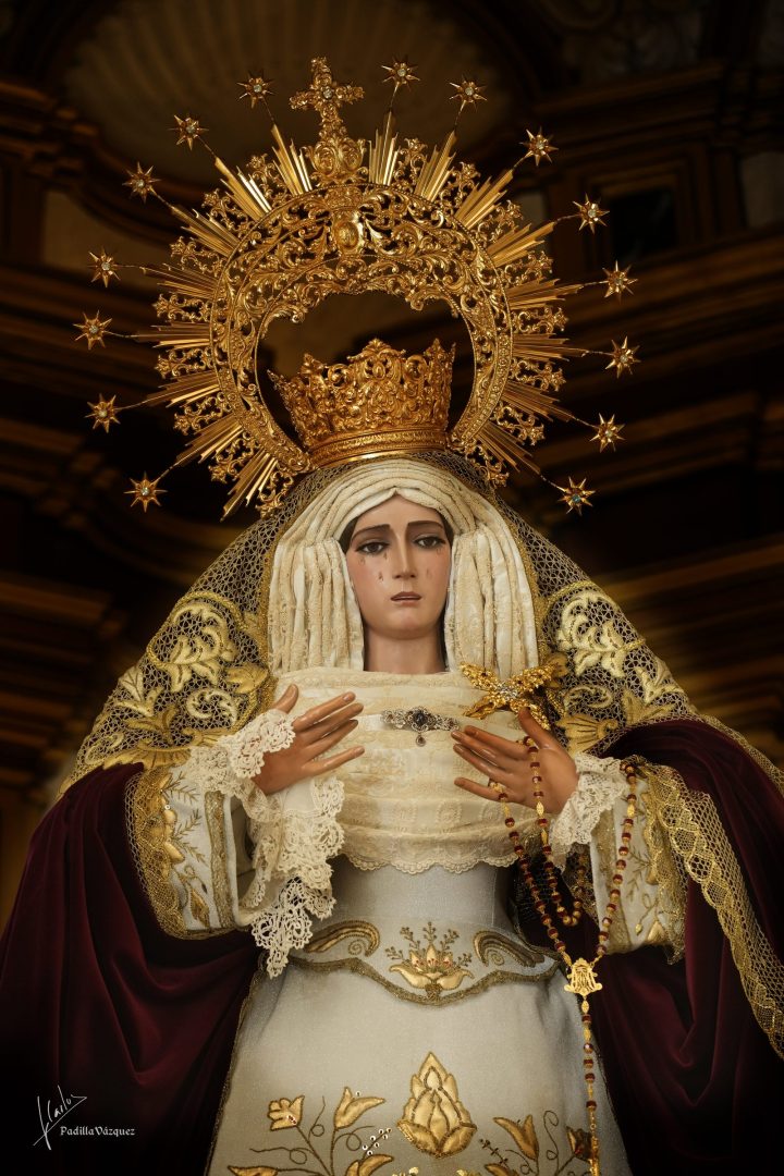 María Santísima de los Dolores, con corona y ráfaga de estrellas, manto granate y rosario entre las manos