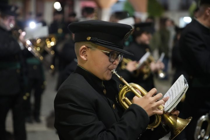 Un joven músico de banda toca la corneta durante la procesión