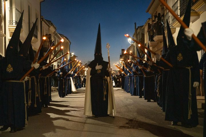 Rows of nazarenos of the Cristo Ultrajado with lit candles and, in the centre, one holding a staff