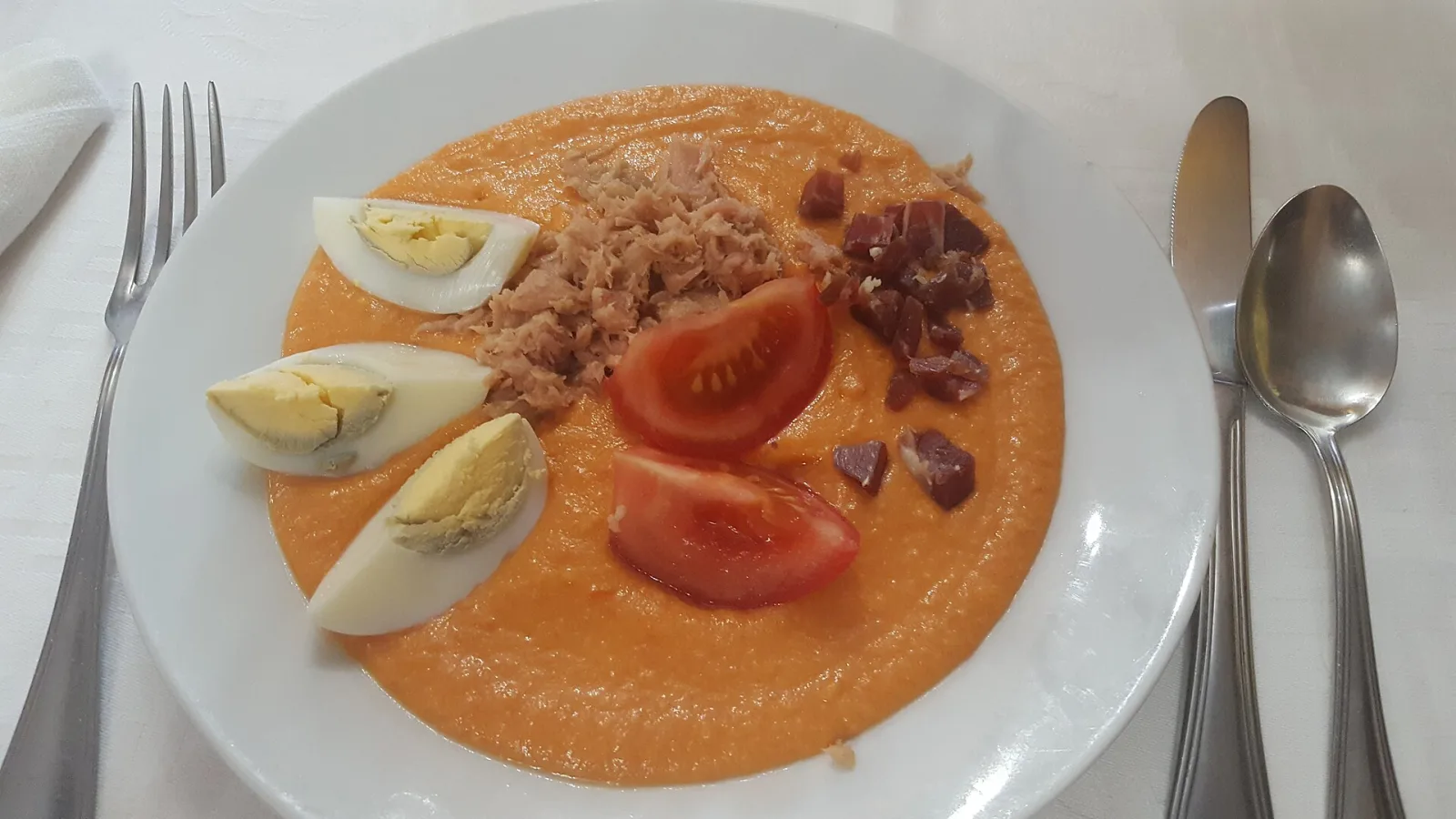A plate of porra antequerana, a thick cold tomato soup, topped with egg, tuna and ham