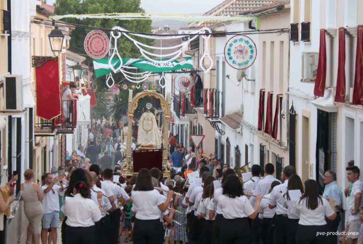 San Benito Abad en procesión por una calle engalanada para sus fiestas, precedido por una banda de música