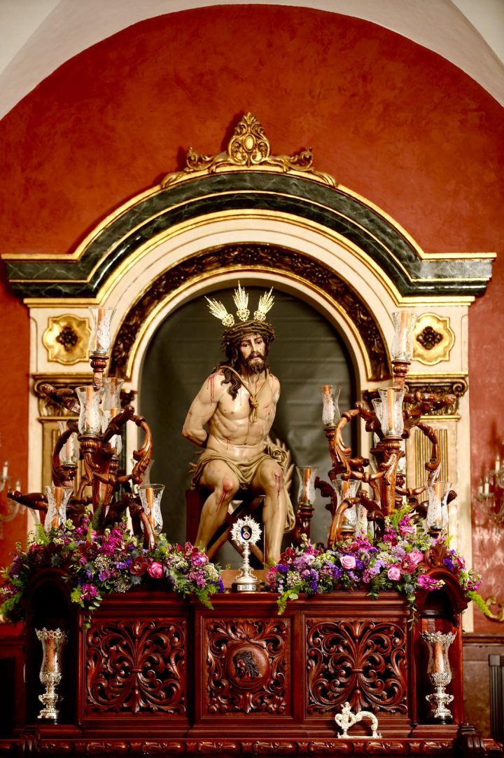 The Santísimo Cristo Ultrajado on his trono before the altarpiece, among candelabra and flowers