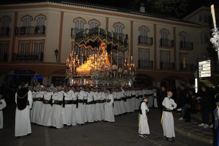 El trono de María Santísima de los Dolores bajo palio, de noche, con la candelería encendida, a hombros de sus portadores